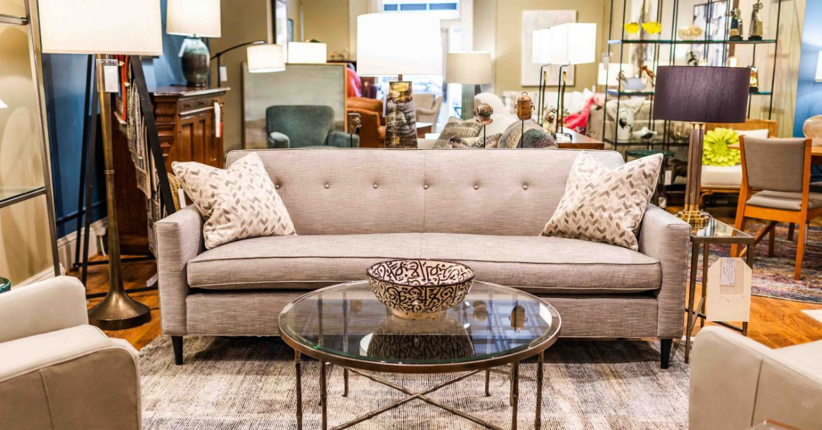 A beige couch with two pillows on each end, 2 beige chairs, and a coffee table with a bowl on top