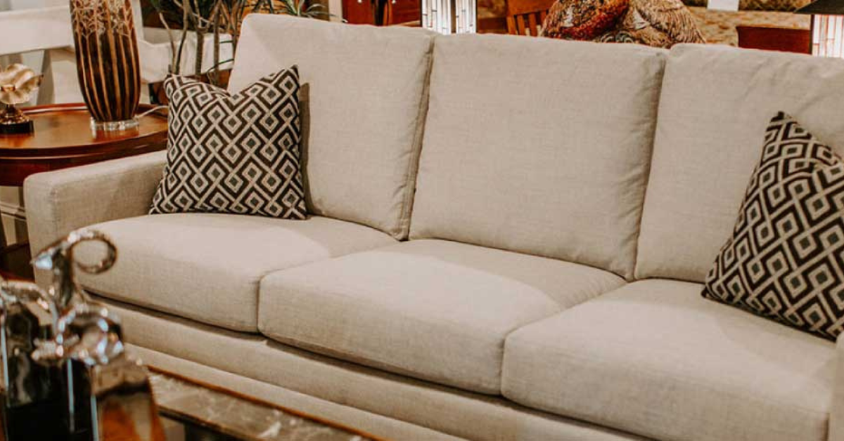 A beige colored couch with dark colored pillows on each end of the couch