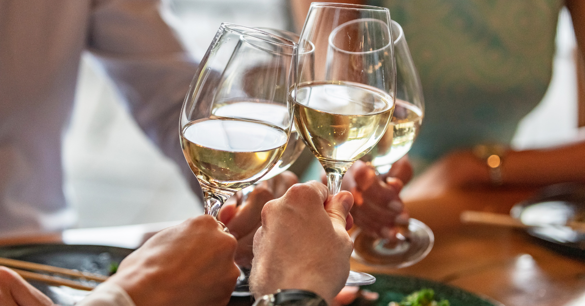 4 people making a cheers with glasses of white wine