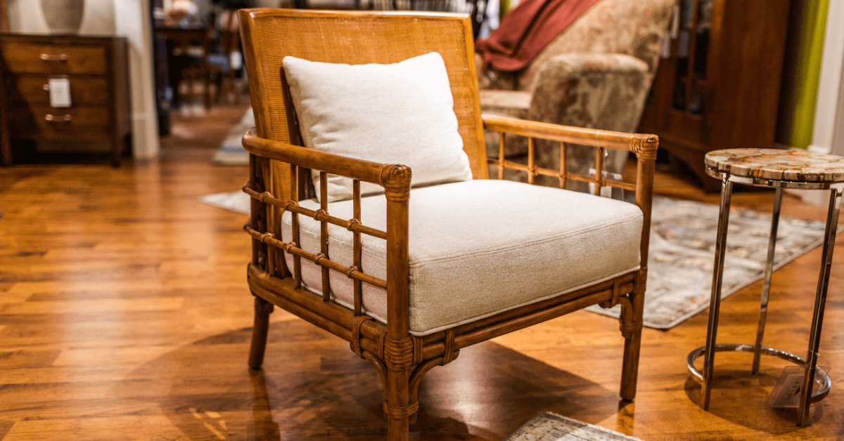 A brown, wooden looking chair with a matching set of a light colored cushion and a pillow