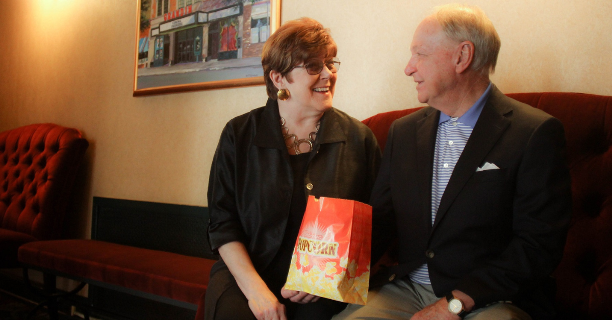 Bill and Andrea looking at each other laughing while holding a bag of popcorn from the Grandin Theatre