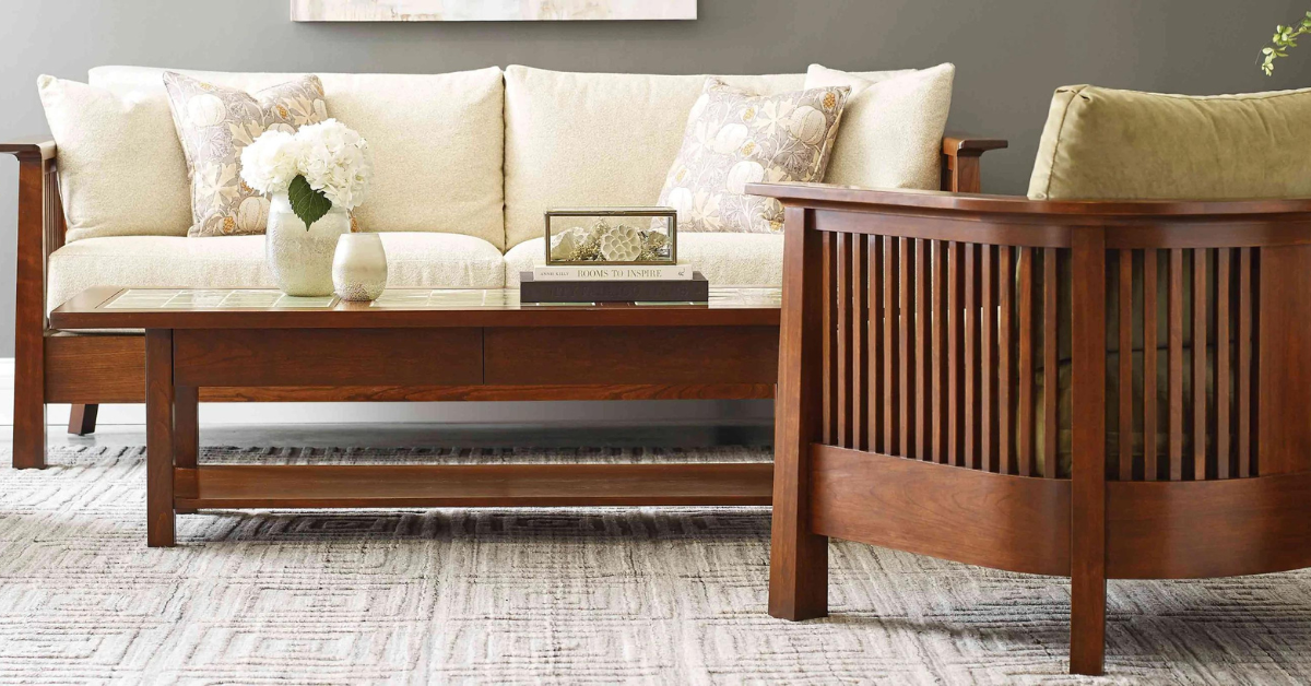 A white stickley couch with a wooden frame and a chair facing away from the camera and towards to the couch