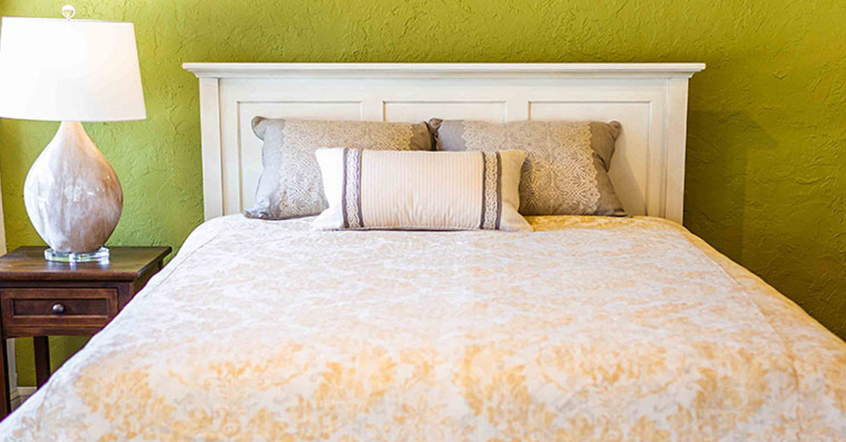 A made bed with white linnens and a nightstand with a lamp up top