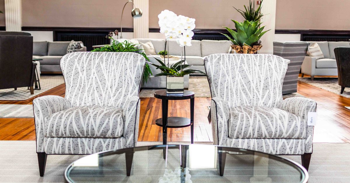 Two gray arm chairs with a coffee table in front, a small table between the chairs, and some couches and chairs in the background